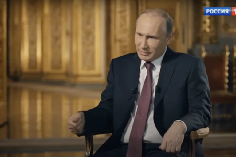 A man in a suit sits on a chair.