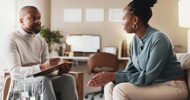 A woman speaks to a man who is writing something down on a clipboard