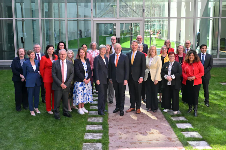 A group of senators stand together and smile in a courtyard
