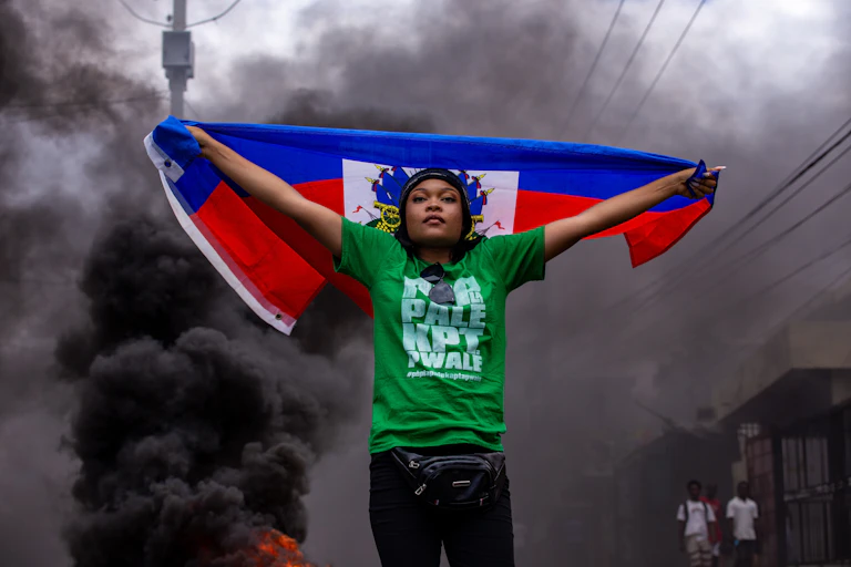A woman holds a flag during a protest against insecurity and violence in Port-au-Prince.