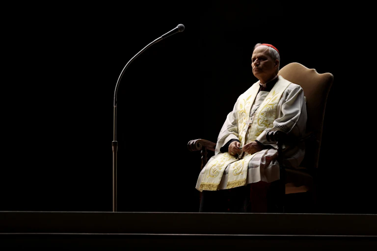 Sacerdote sentado junto a un micrófono