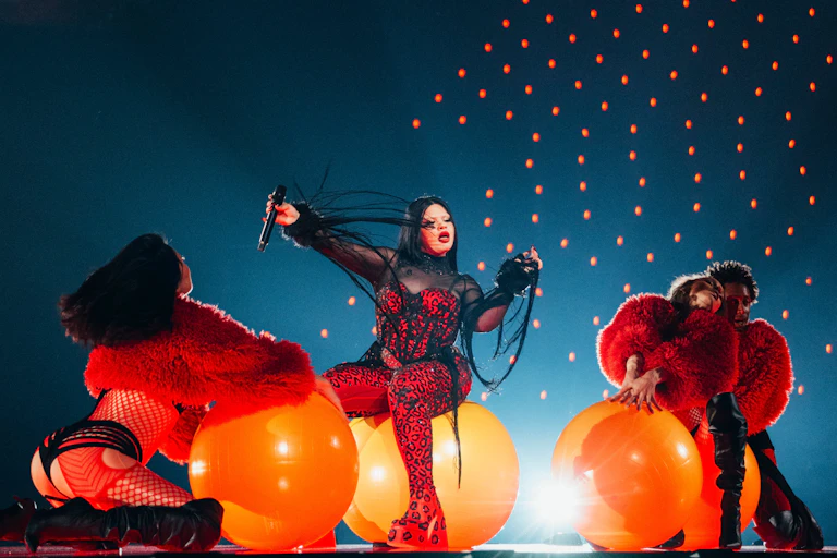 a woman on stage sat on an orange space hopper.