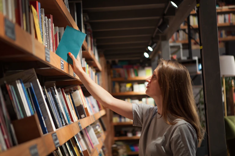 A woman pulling a book off a self
