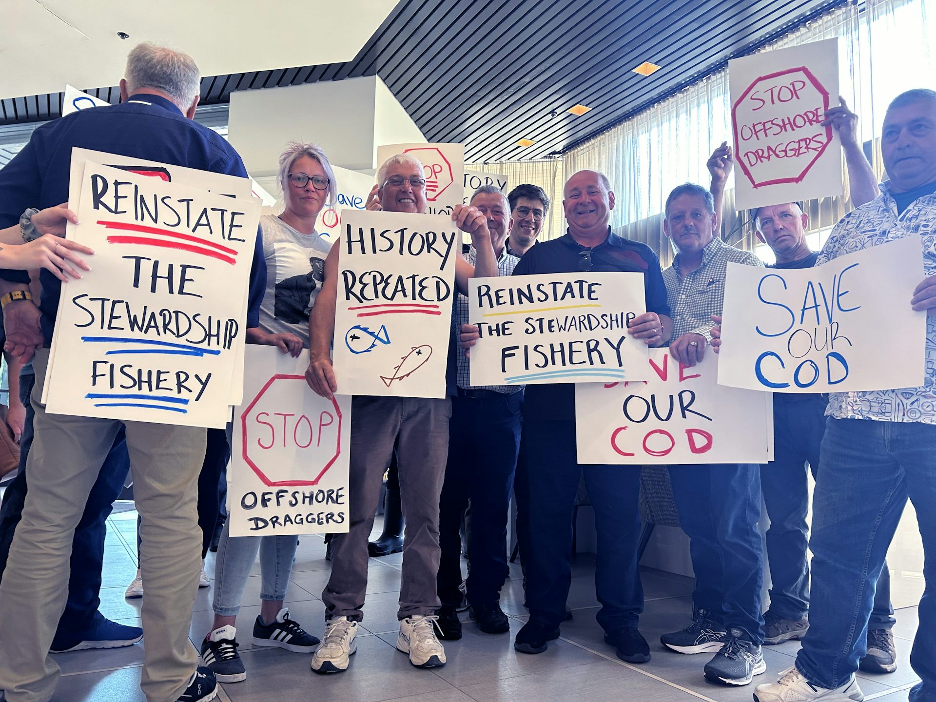 El grupo de personas mantiene las señales que protestan por la reapertura de la pesca comercial de pasteles.