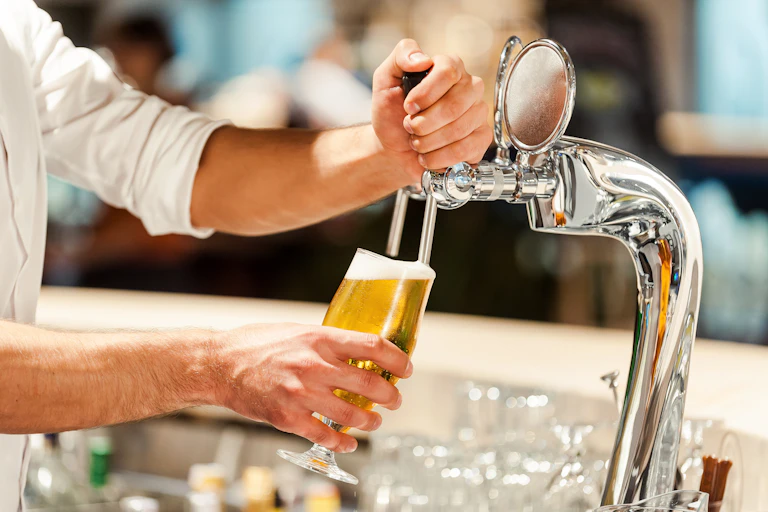 bartender pours beer into a glass