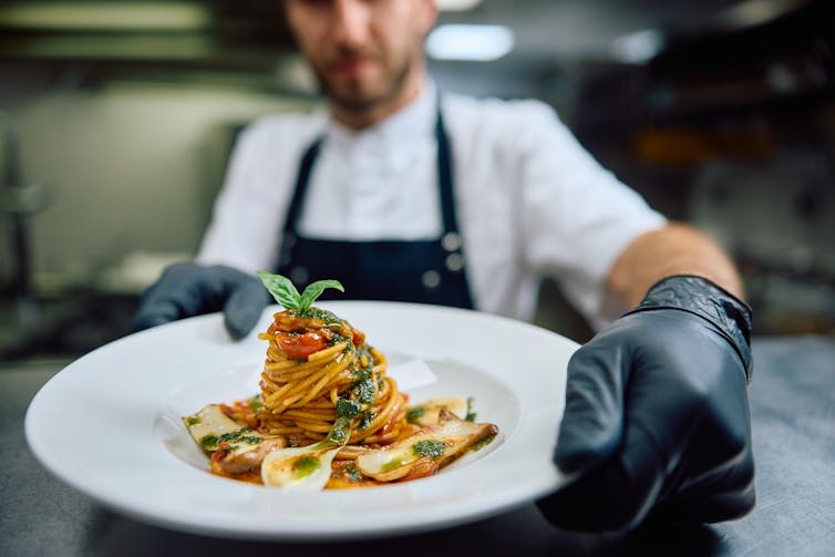 Chef holding plate of spaghetti
