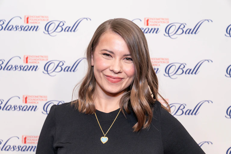 Bindi Irwin smiling in front of a backdrop that reads 'Blossom Ball'.