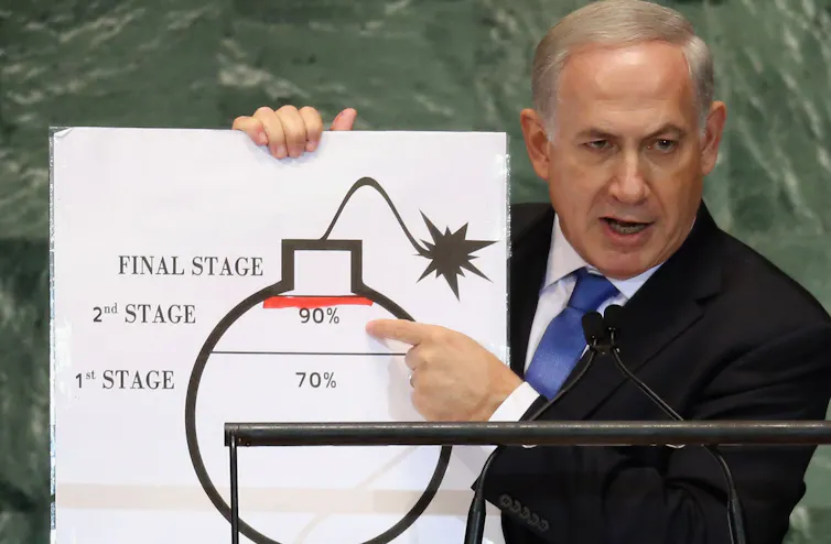 A man holds a placard with a fake cartoon bomb.