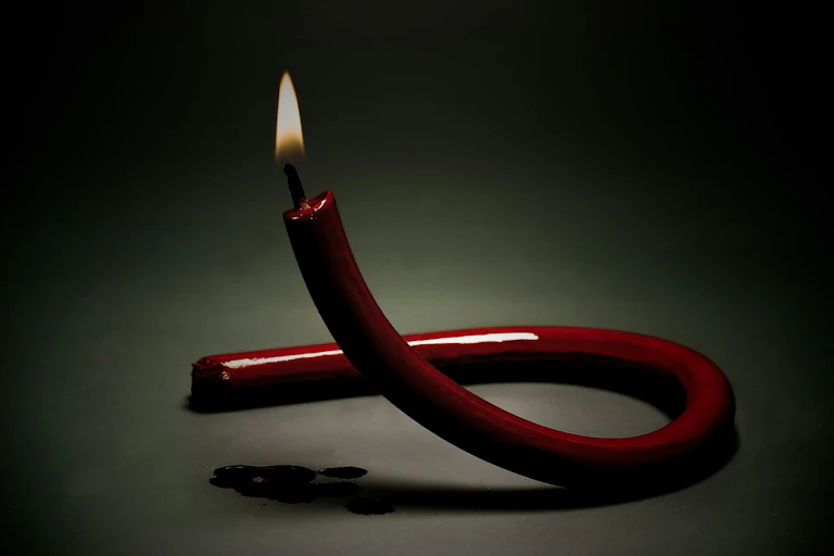 Red candle twisted into the shape of the HIV ribbon logo