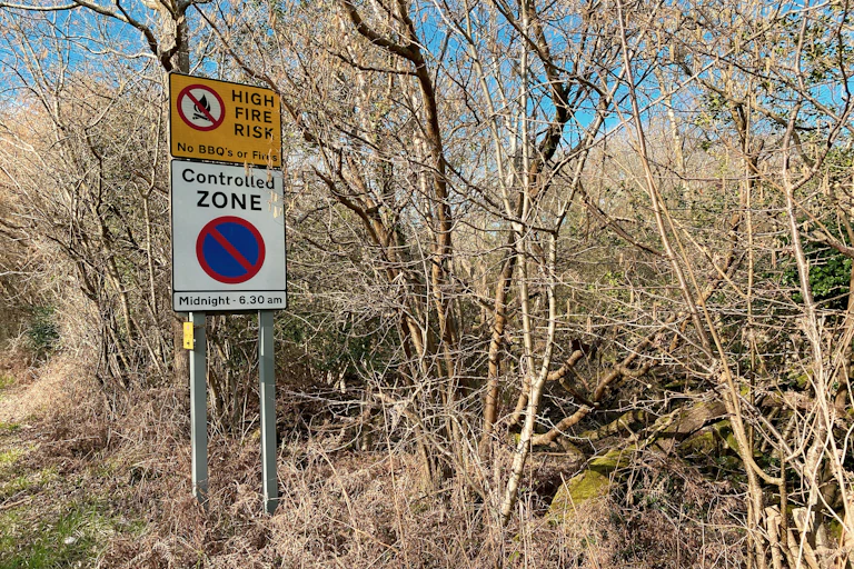 A sign declaring a high fire risk near a wooded area.