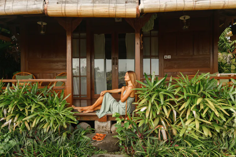 woman sititng by wooden hotel accommodation in forest