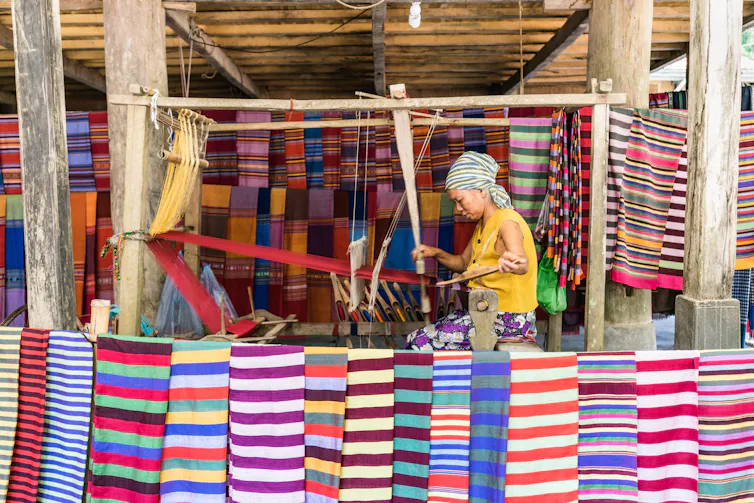 woman weaving, selling fabrics at market in Vietname