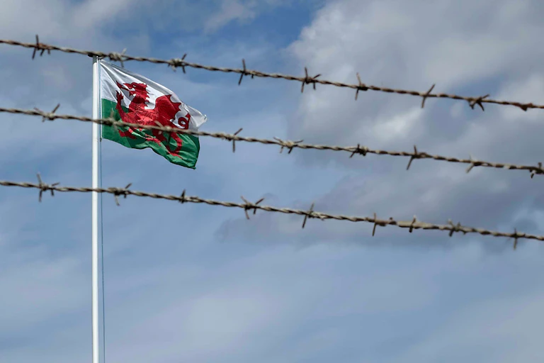 The Welsh flag flying behind barbed wire.