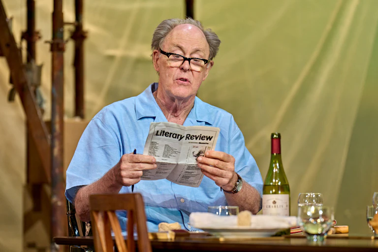 John Lithgow reading a prop copy of the Literary Review