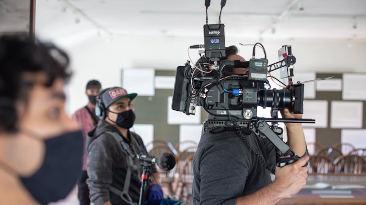 A person points and holds up a film camera