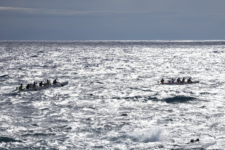 two canoes, each with several crew, out on the water