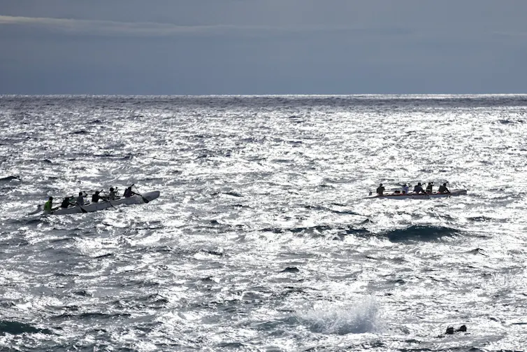 two canoes, each with several crew, out on the water