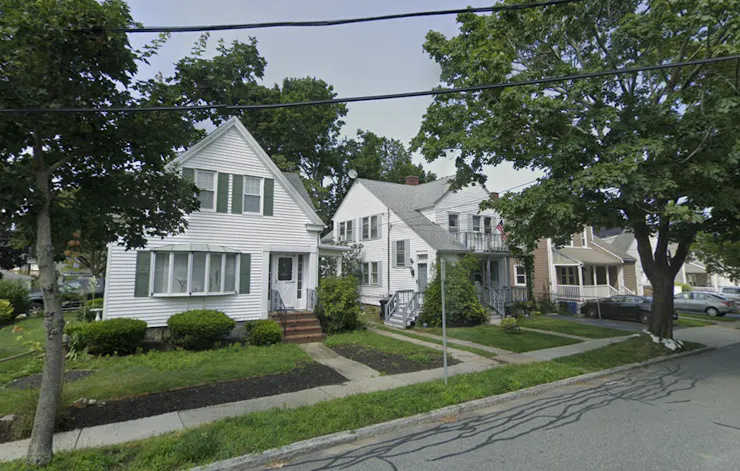 Three homes side by side on a leafy suburban street.