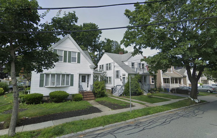 Three homes side by side on a leafy suburban street.