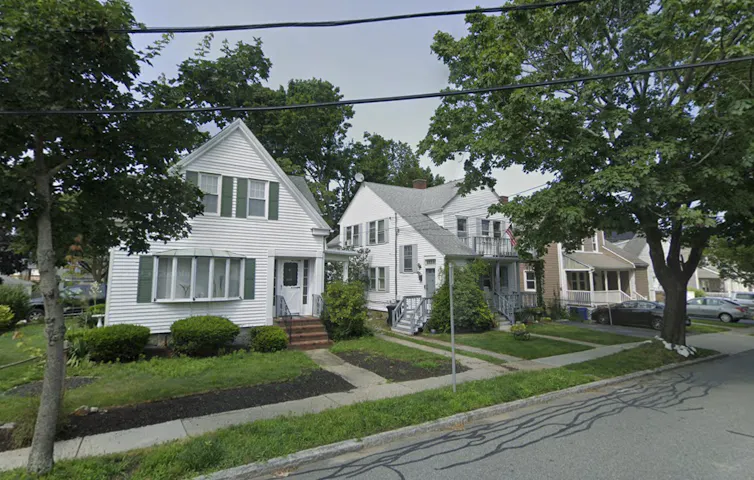 Three homes side by side on a leafy suburban street.