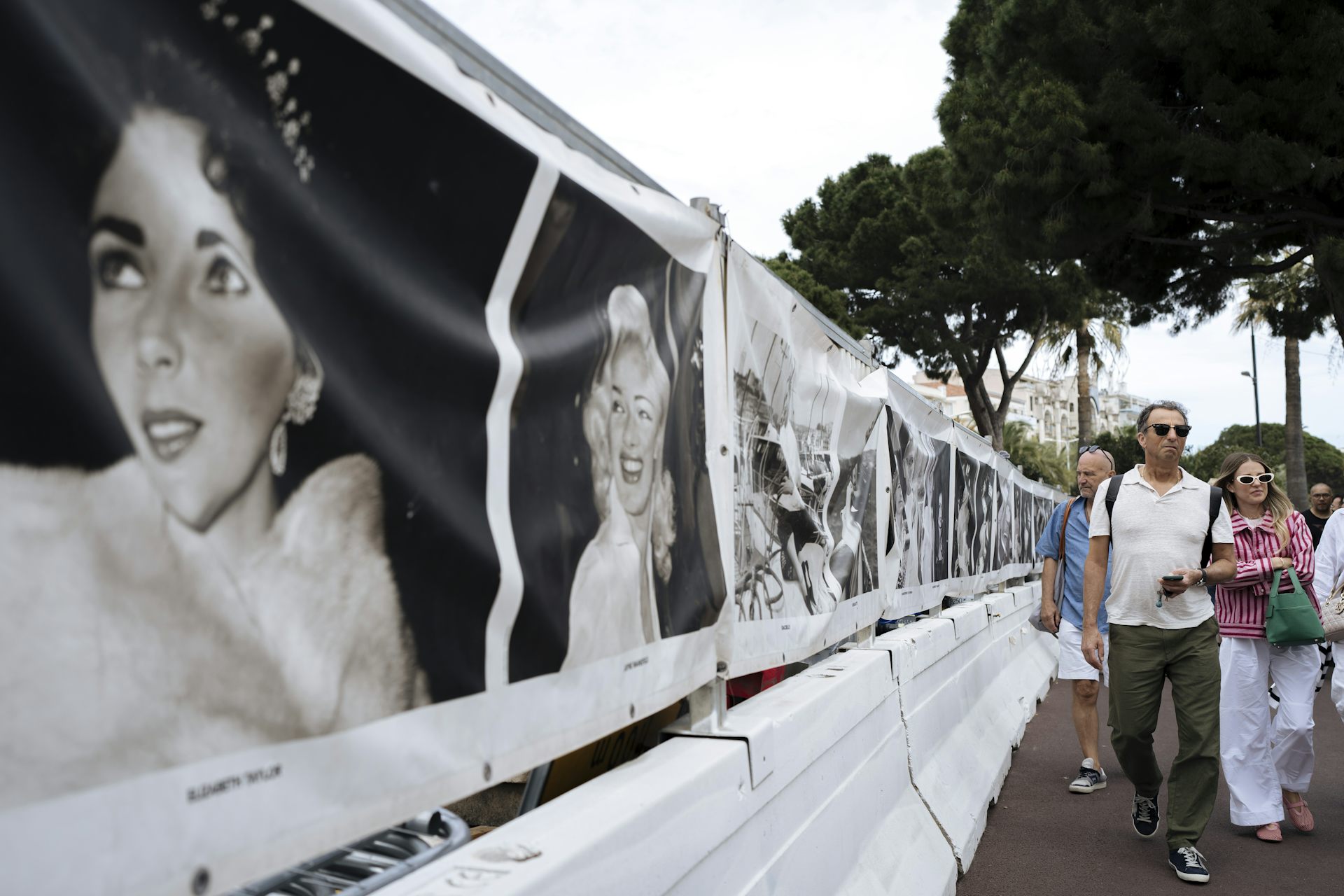 La gente camina una serie de carteles de películas en blanco y negro de actores de Hollywood.