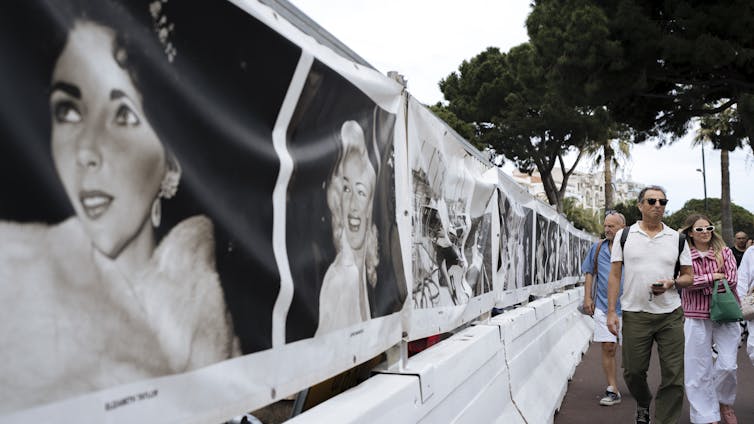 La gente camina una serie de carteles de películas en blanco y negro de actores de Hollywood.