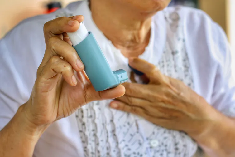 Elderly woman's hands holding a blue inhaler.