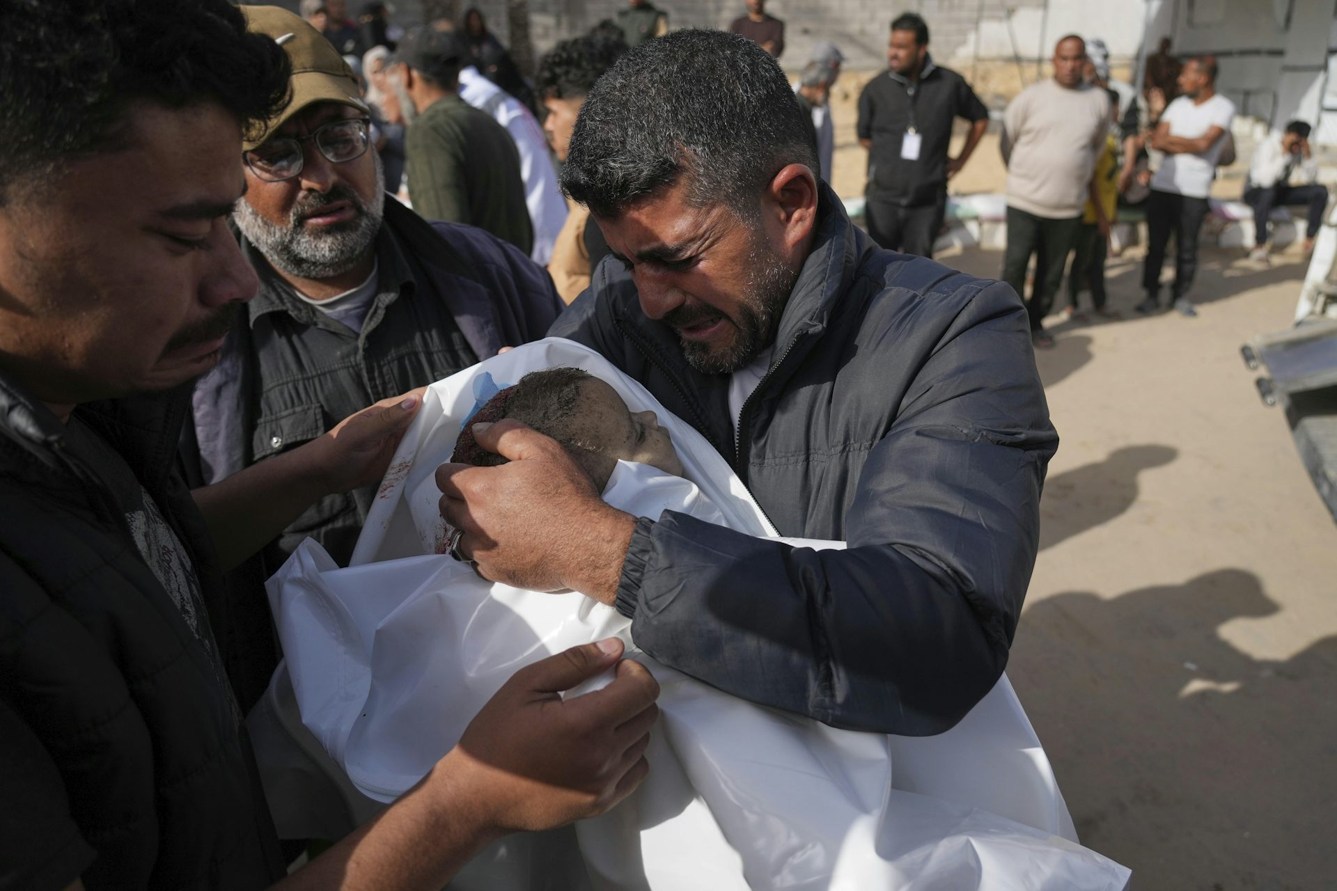 Un homme tient un enfant mort dans ses bras