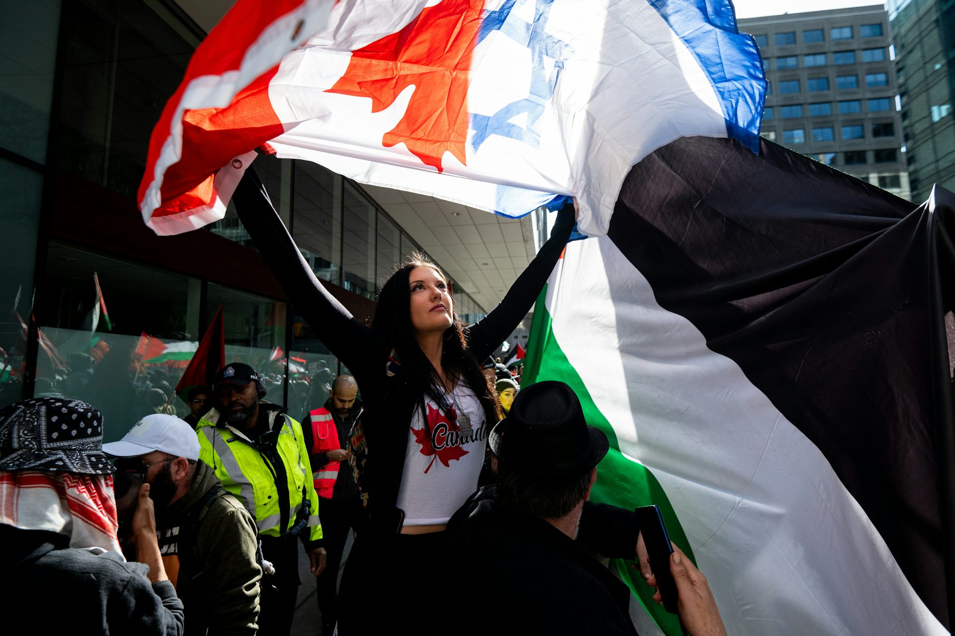 Une femme brandit un drapeau canadien et israélien devant des manifestants palestiniens
