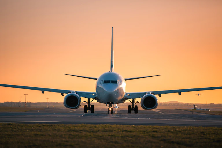 An airplane is visible on a runway at sunset.