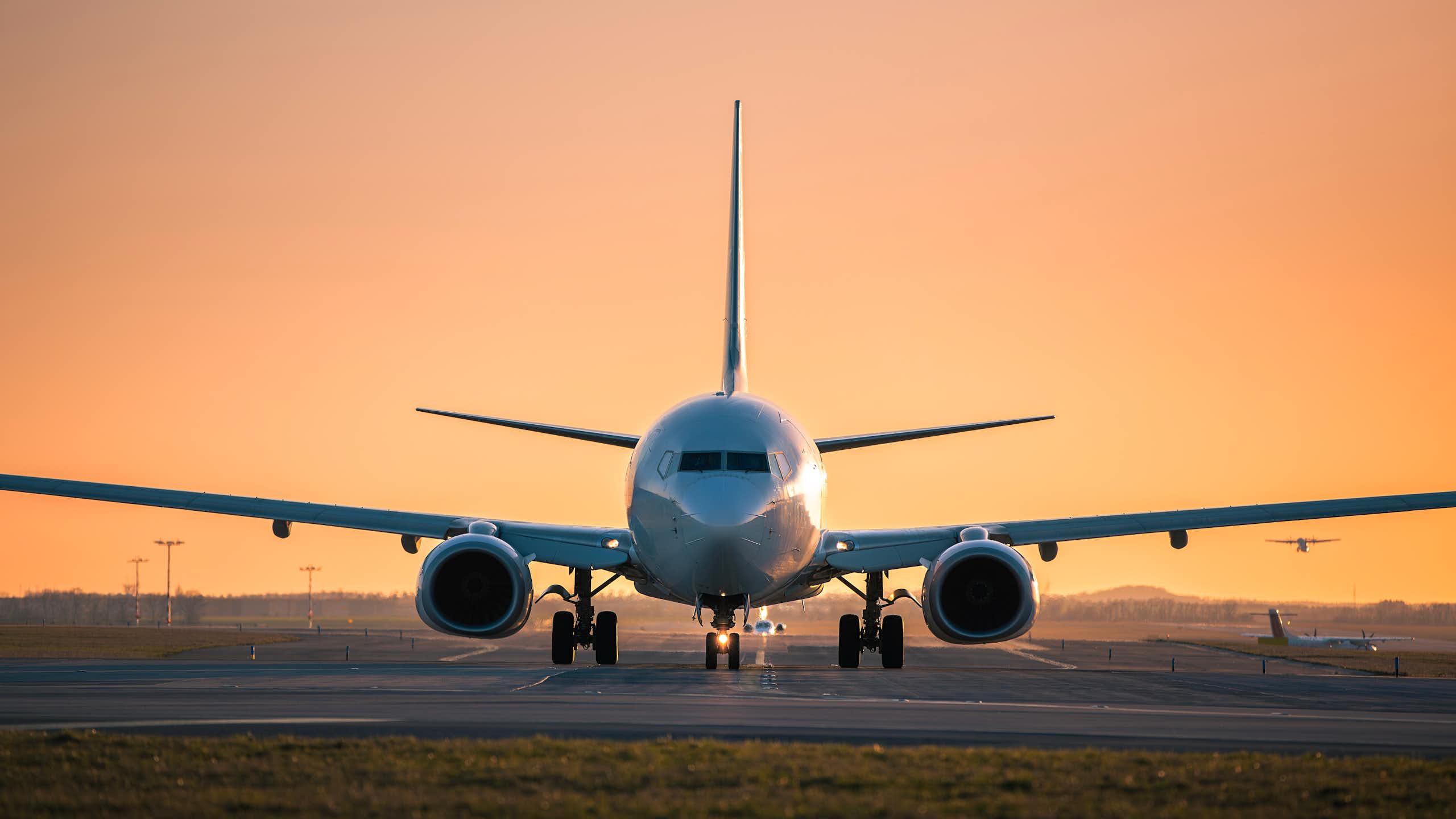 An airplane is visible on a runway at sunset.