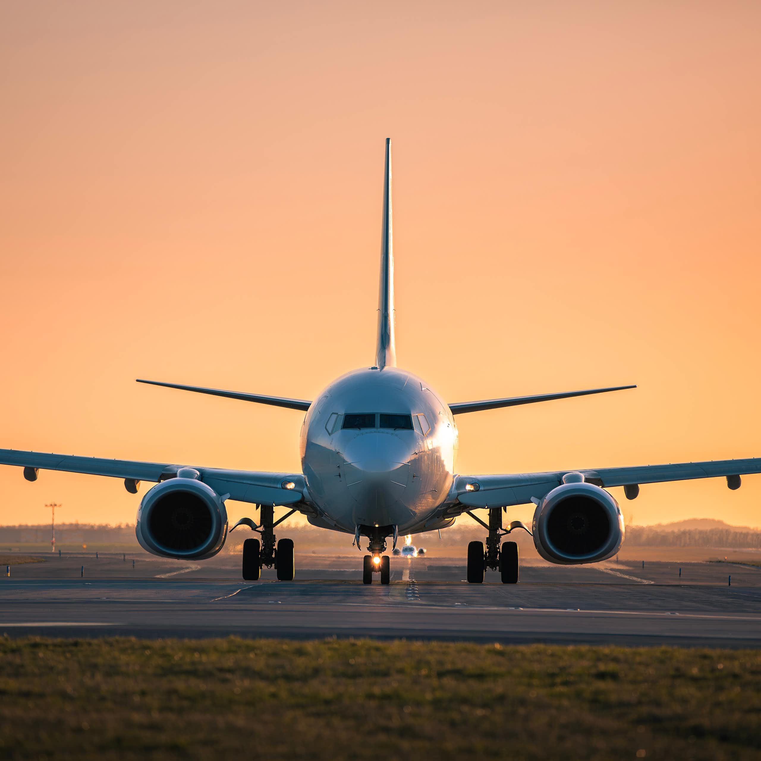 An airplane is visible on a runway at sunset.