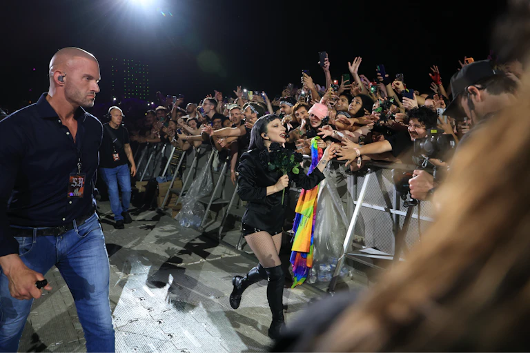 A woman waves a rainbow flag in front of a crowd.