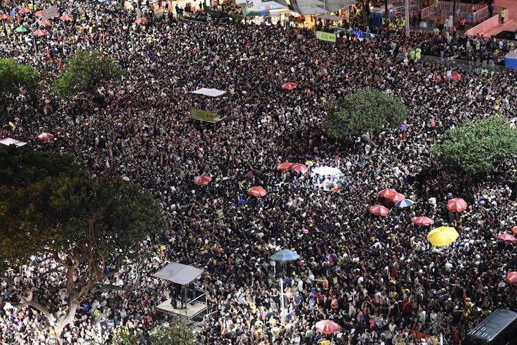 A crowd of people interspersed by umbrellas