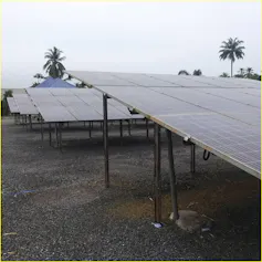 A few rows of solar panels standing on the soil in a rural area