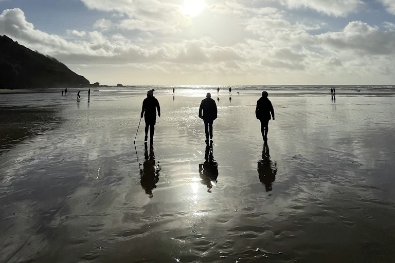 three people walking on beach, sea reflections