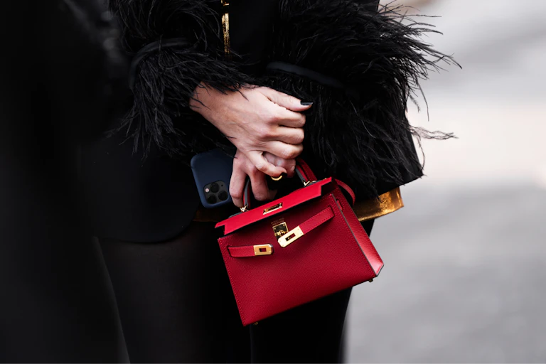 Manos de mujer sujetando un bolso rojo y un móvil