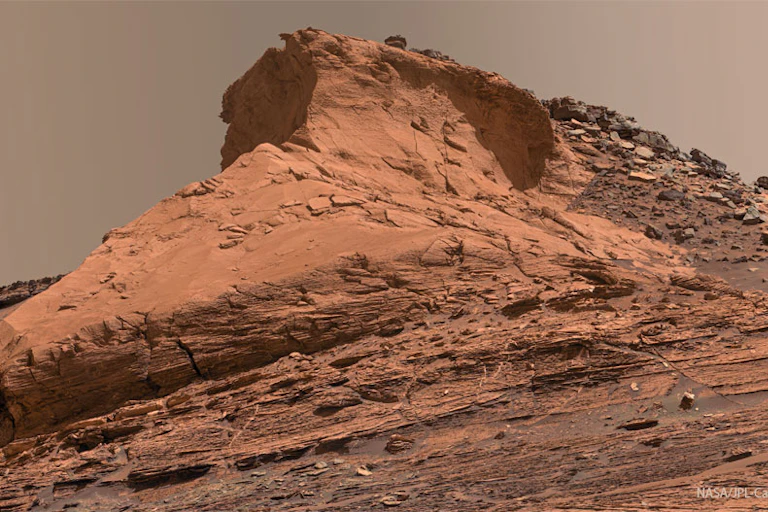 A rocky mound, colored rusty red.