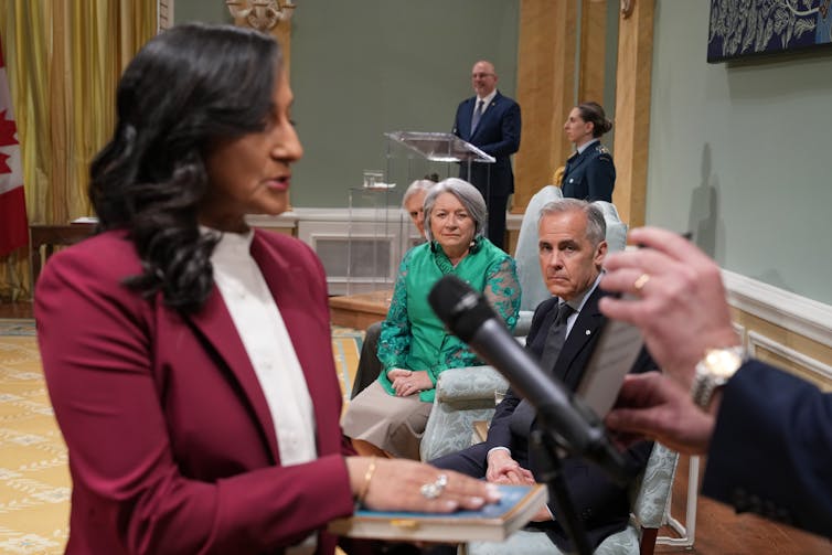 Una mujer con el cabello oscuro a lo largo del hombro con una lucha por luchar contra el juramento como un hombre con un cabello gris corto para pensar en la distancia.