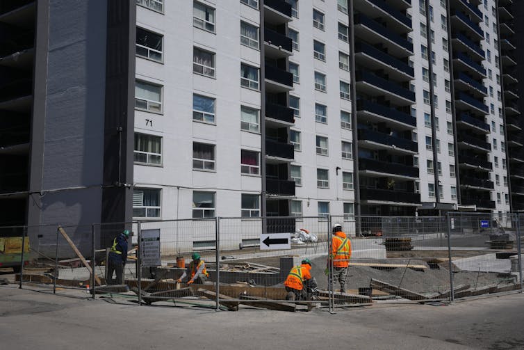 Los trabajadores de la construcción trabajan fuera de un edificio residencial