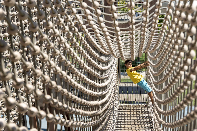 Little boy navigates an outdoors ropes course.