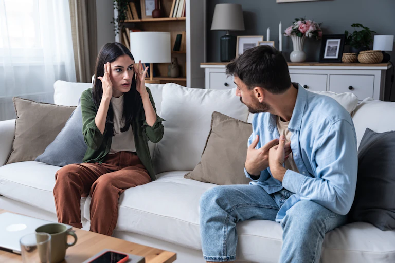 A man and woman sitting on a couch having an argument