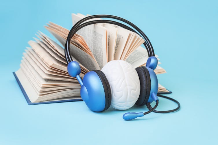 Open book and brain in headphones on blue background.