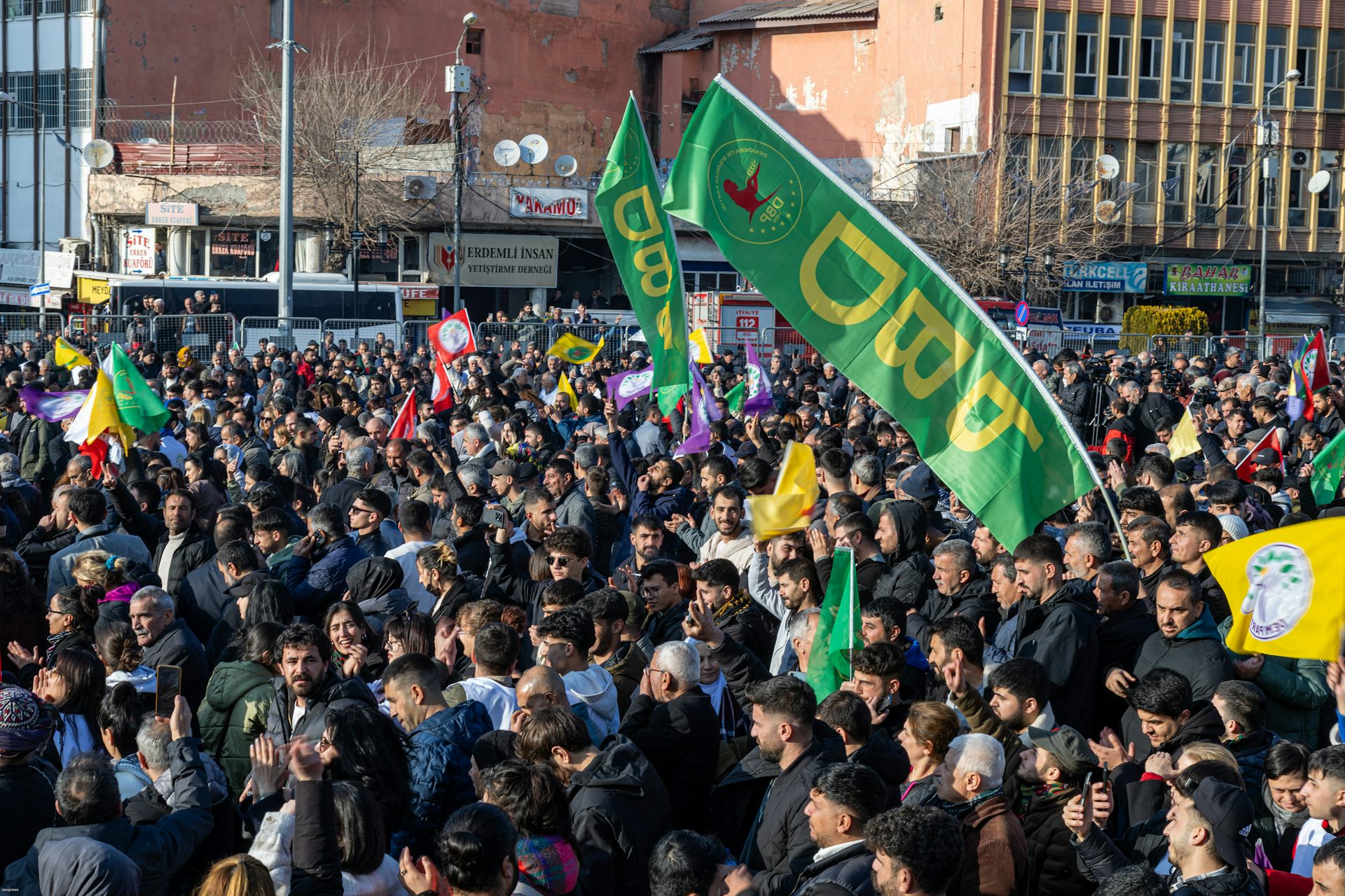 A crowd of Kurds waving green and yellow flags.