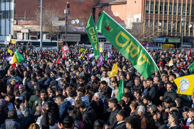 A crowd of Kurds waving green and yellow flags.