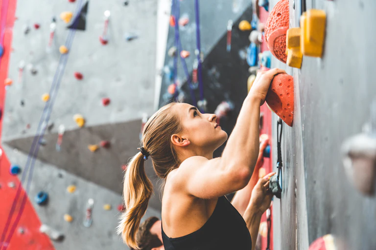A woman scales a rock climbing wall.