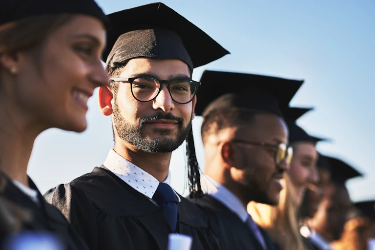 Graduates in cap and gown, one looking at camera
