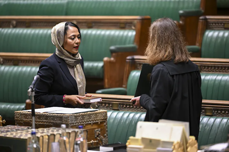Rushanara Ali being sworn into the House of Commons with her hand on an unidentifiable religious text.