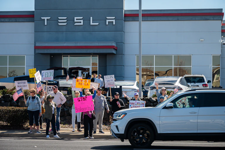 Manifestantes con pancartas delante del concesionario de Tesla