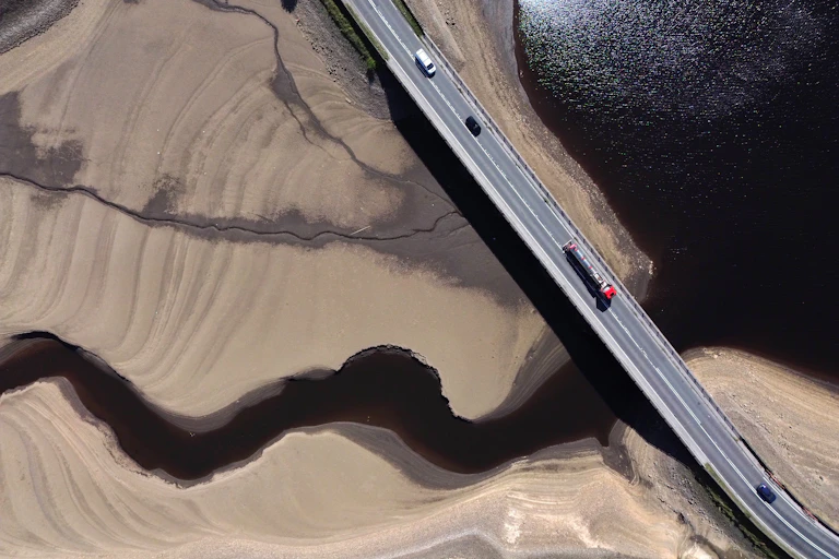 An aerial view of a motorway bridge over a dry river bed.